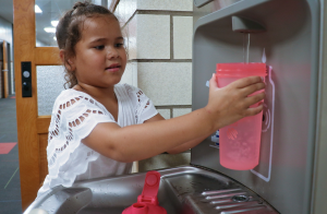 A student fills their water bottle on a hot school day in a non-air-conditioned school.